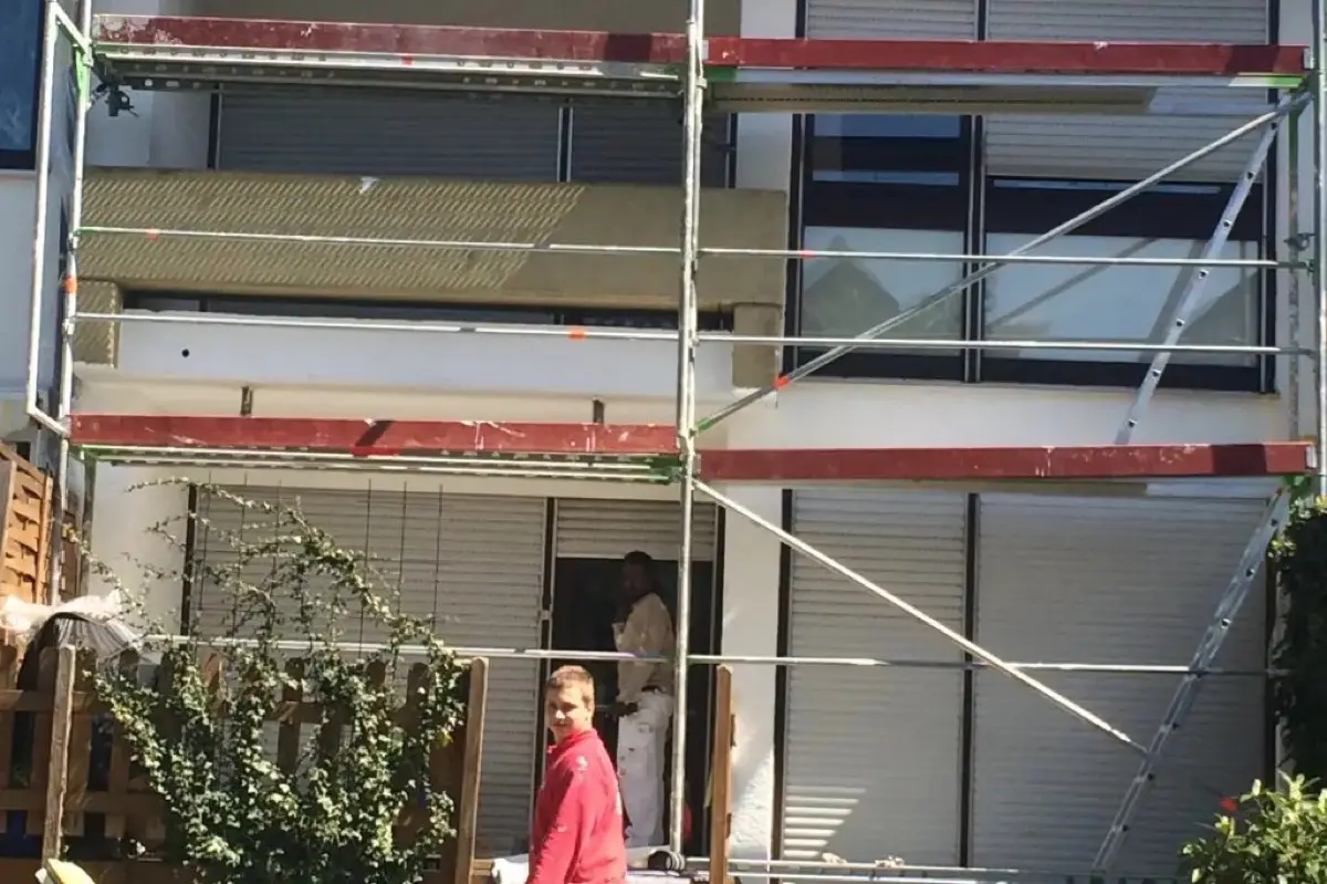 Fassadenanstrich Reihenhaus Karben — Gerüst, Andymen-Maler in roter Jacke