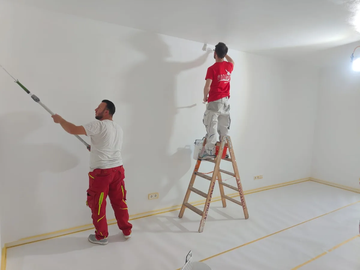 Zwei Andymen-Maler streichen Wand und Decke in Frankfurt-Westend