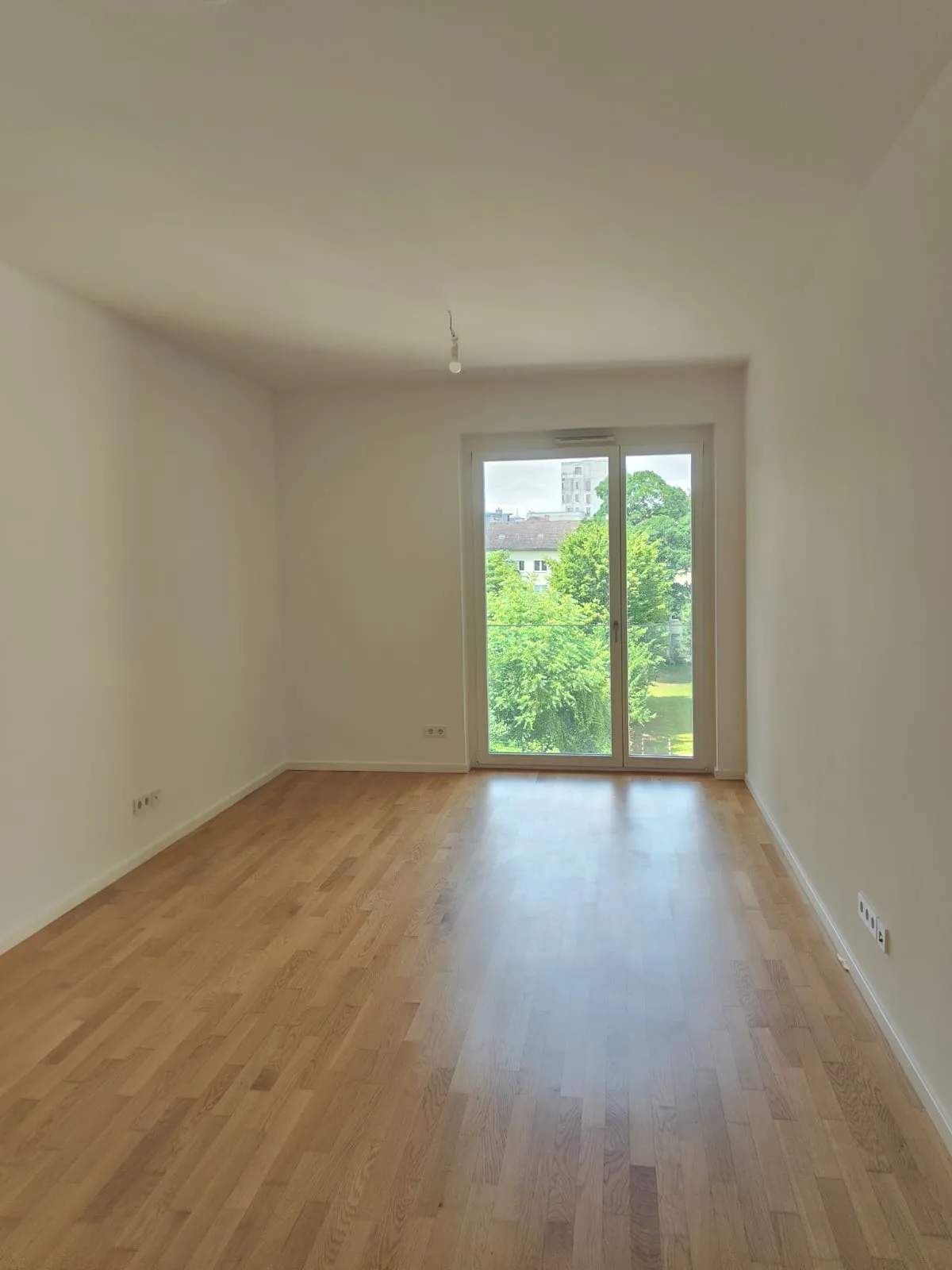 Schlafzimmer fertig gestrichen mit Holzparkett und bodentiefen Fenstern