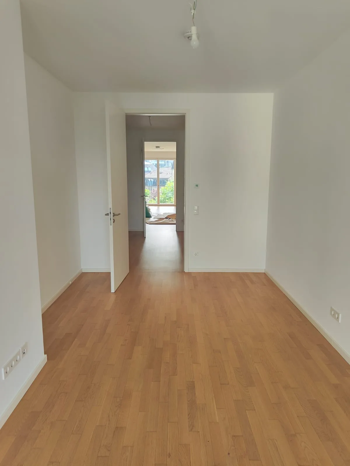 Drittes Zimmer fertig gestrichen mit Holzparkett und Durchblick zum Wohnzimmer