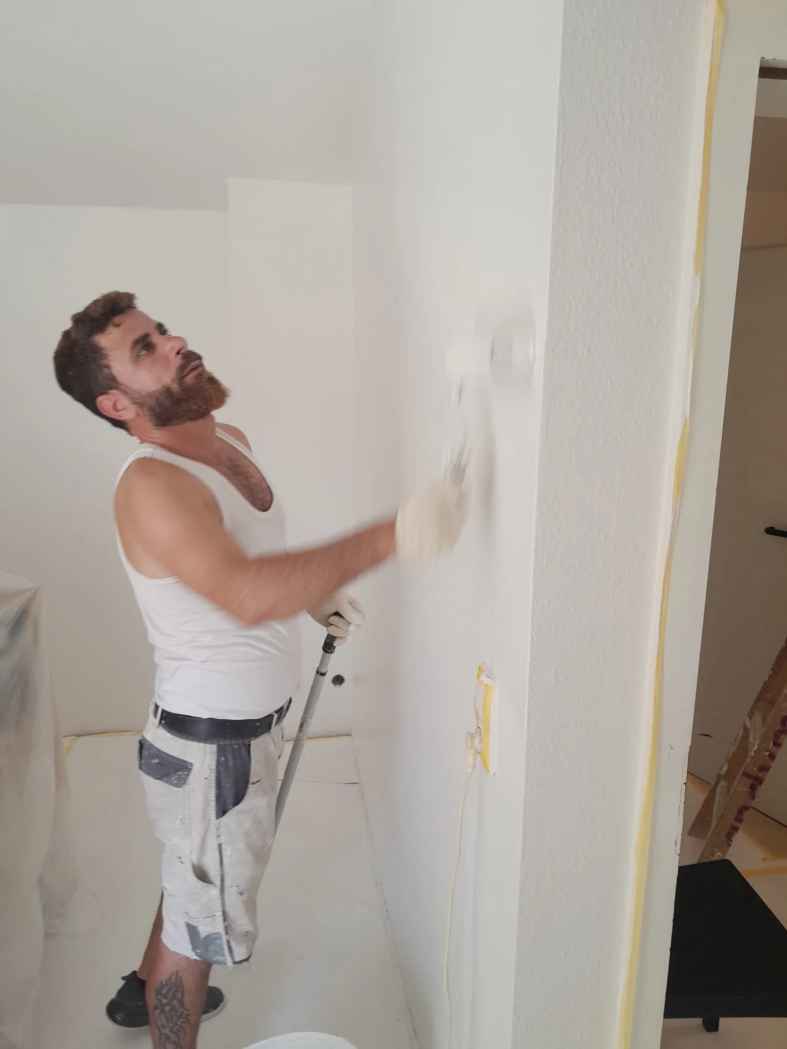 Maler streicht Wandecke praezise nach Silikonarbeit an Dachfenster Hochheim